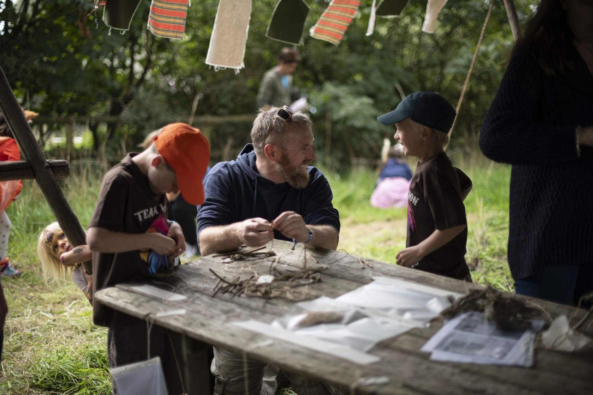 A man working with happy children to create nature-based crafts