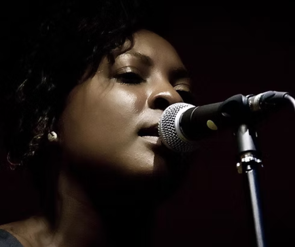 A woman stands and is singing into a microphone.