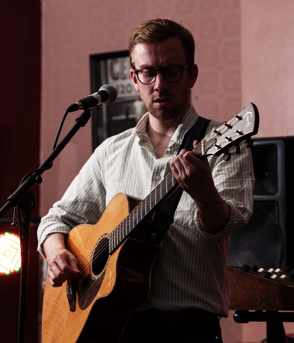 Benedict Hawkin playing acoustic guitar.