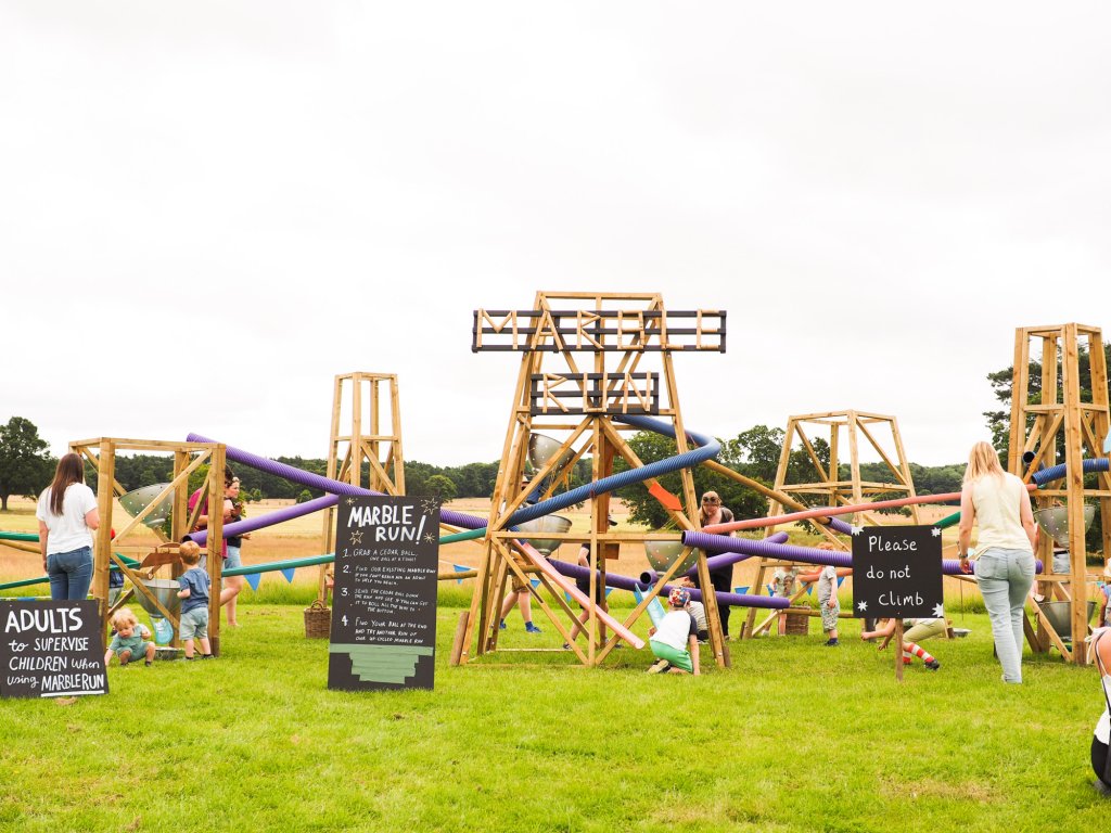 A giant wooden marble run being played with by children and adults.